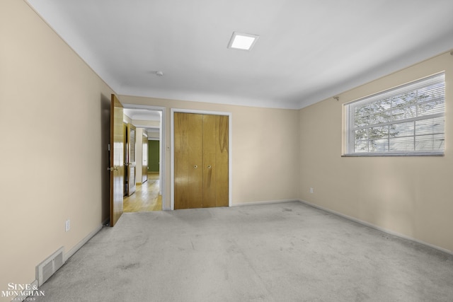 unfurnished bedroom with carpet flooring, baseboards, visible vents, and a closet