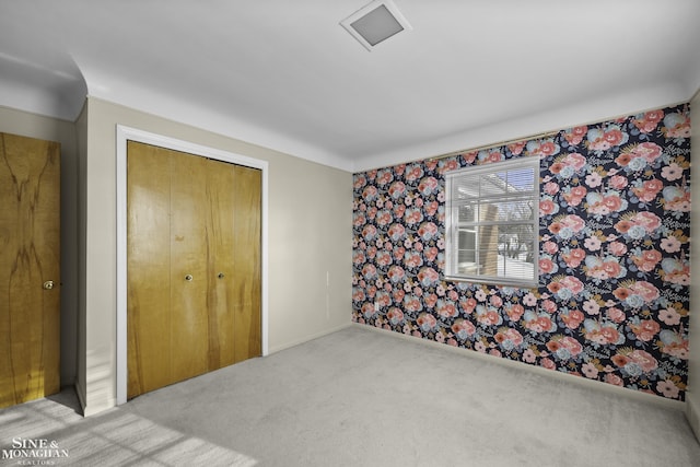 carpeted bedroom featuring a closet, visible vents, wallpapered walls, and baseboards