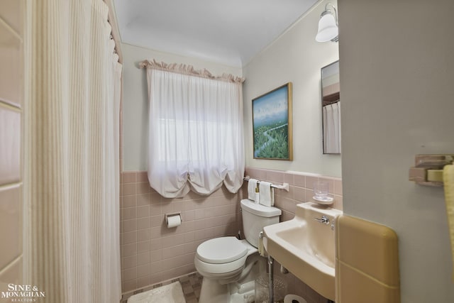 full bath featuring a wainscoted wall, toilet, tile walls, and a shower with shower curtain