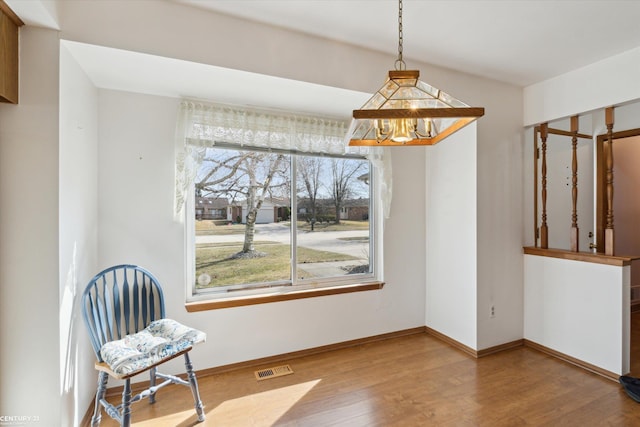 living area featuring a notable chandelier, visible vents, baseboards, and wood finished floors