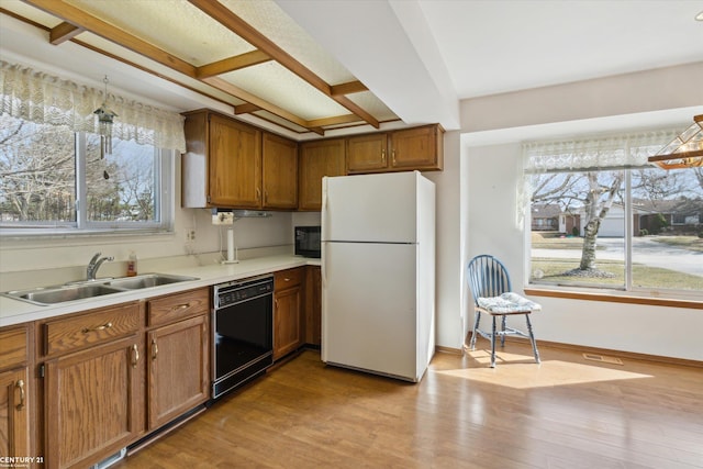 kitchen featuring brown cabinets, black appliances, light wood-style floors, and a sink