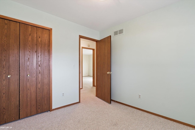 unfurnished bedroom featuring light carpet, visible vents, a closet, and baseboards