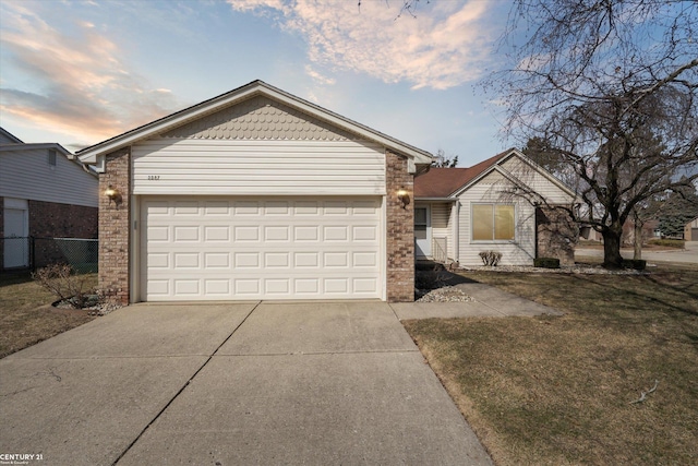 ranch-style home with concrete driveway, an attached garage, fence, and a yard