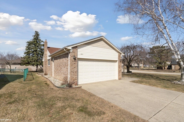 view of side of home with a chimney, concrete driveway, a garage, a lawn, and brick siding