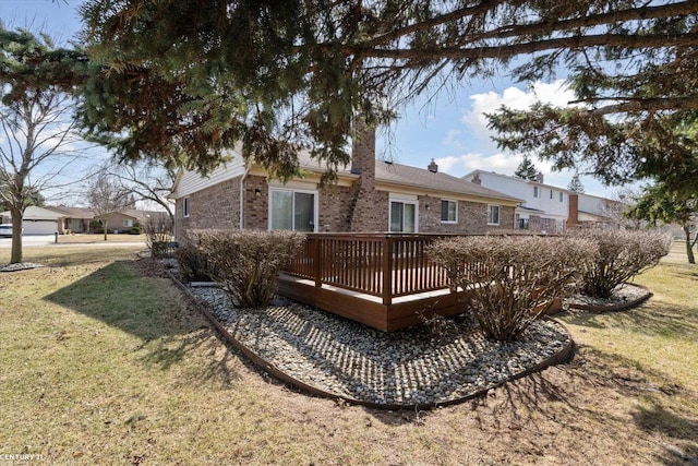 back of house with a yard, a chimney, brick siding, and a wooden deck