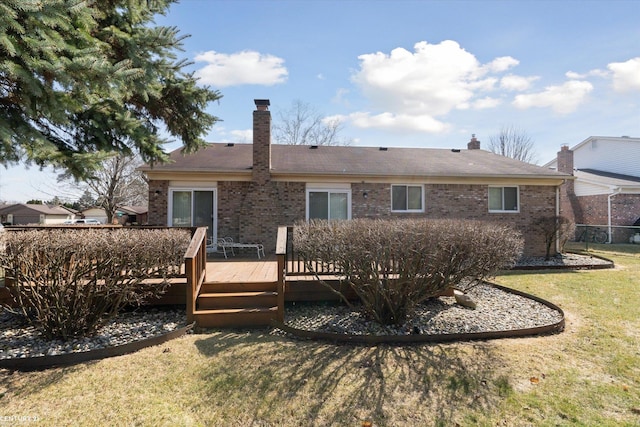 rear view of house with a deck, a yard, brick siding, and a chimney