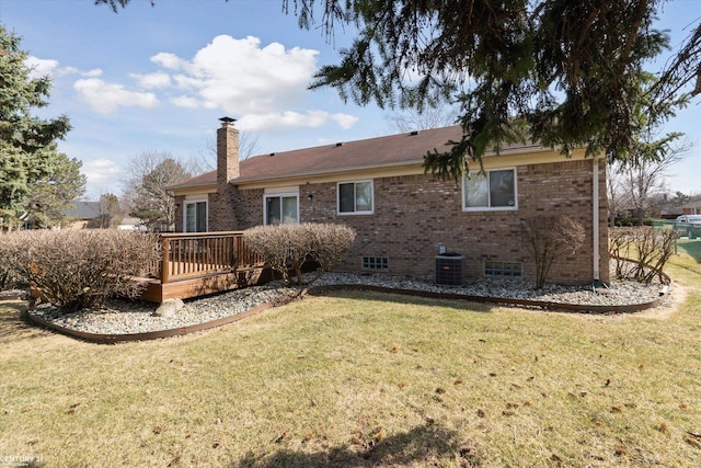 rear view of house with a yard, cooling unit, a wooden deck, brick siding, and a chimney