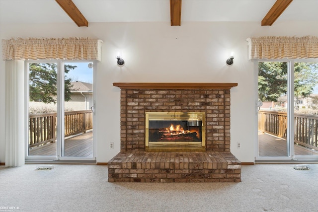 unfurnished living room featuring beamed ceiling, carpet, and a healthy amount of sunlight