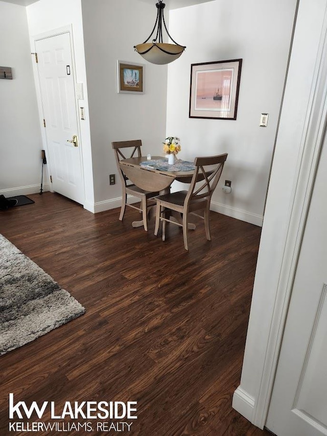 dining area featuring dark wood-type flooring and baseboards