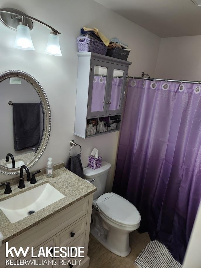 bathroom with curtained shower, toilet, and vanity