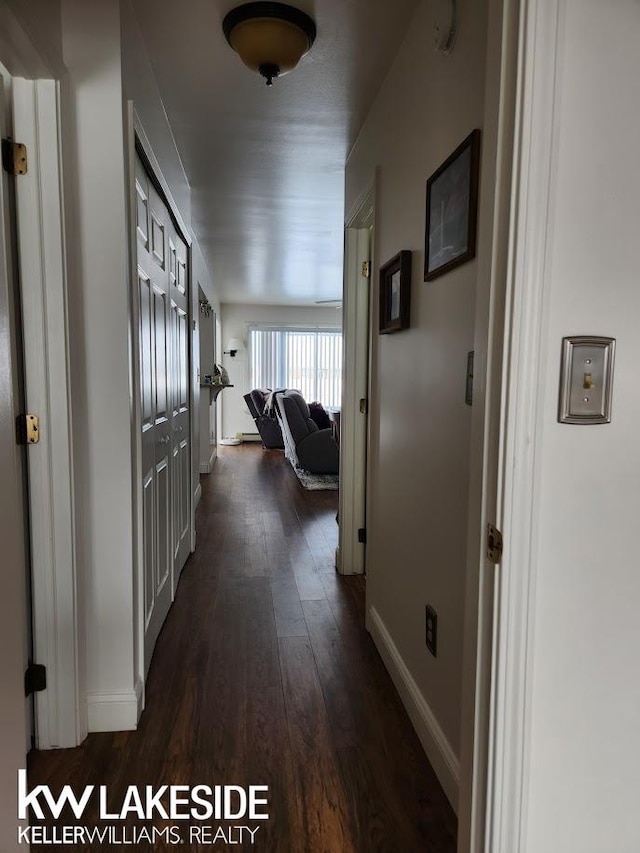 hallway with dark wood-style floors and baseboards