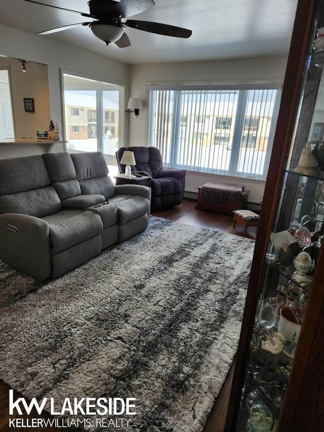 living room featuring a baseboard heating unit, wood finished floors, and a ceiling fan