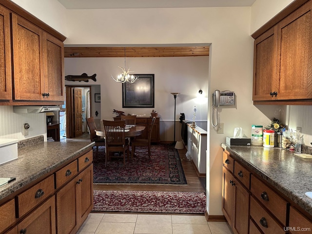 kitchen featuring hanging light fixtures, dark countertops, a notable chandelier, and brown cabinetry