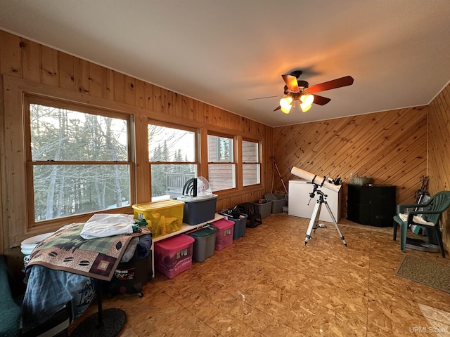 game room featuring tile patterned floors, wooden walls, and a ceiling fan