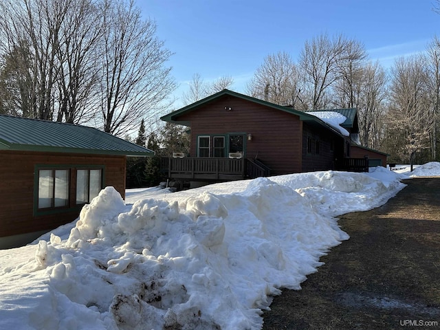 view of snow covered exterior with metal roof and a deck