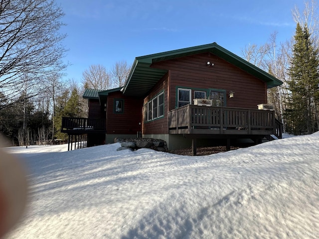 snow covered back of property featuring a wooden deck