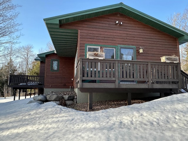 snow covered rear of property with a deck