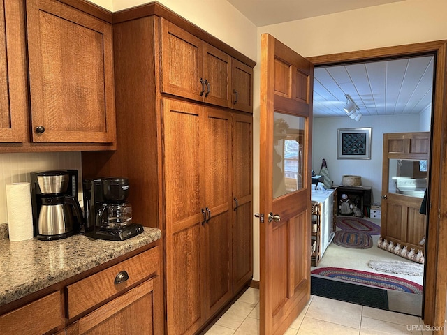 kitchen featuring light tile patterned flooring, light stone countertops, and brown cabinets