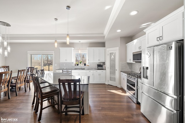 kitchen with tasteful backsplash, pendant lighting, appliances with stainless steel finishes, a kitchen breakfast bar, and a sink