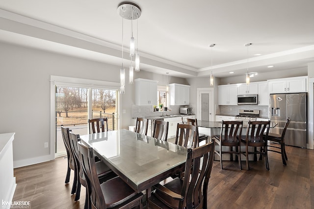 dining space with recessed lighting, baseboards, a raised ceiling, and dark wood-type flooring