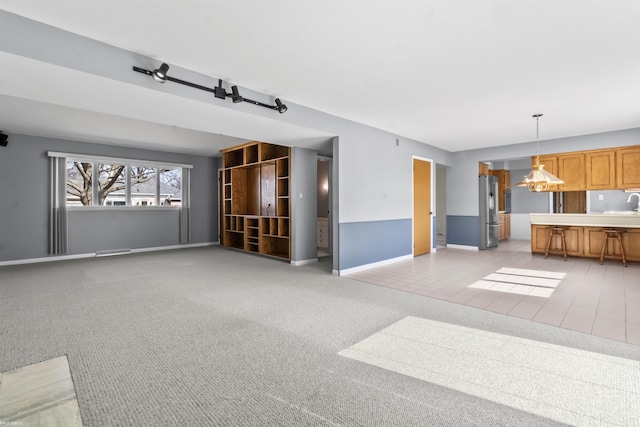 unfurnished living room featuring visible vents, light colored carpet, and baseboards