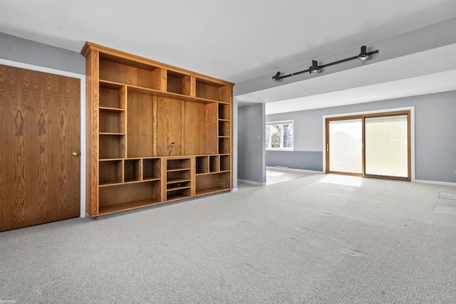 unfurnished living room featuring baseboards and light carpet