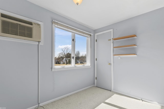 spare room with carpet flooring, a wall mounted air conditioner, and baseboards