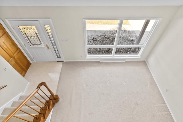 foyer featuring baseboards, stairs, and carpet