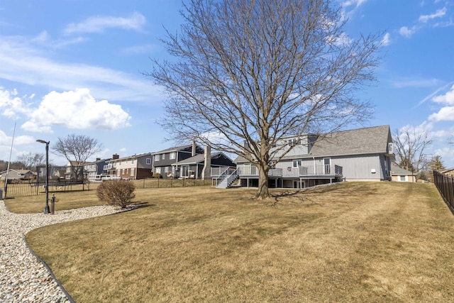 view of yard featuring stairs, fence, a residential view, and a wooden deck