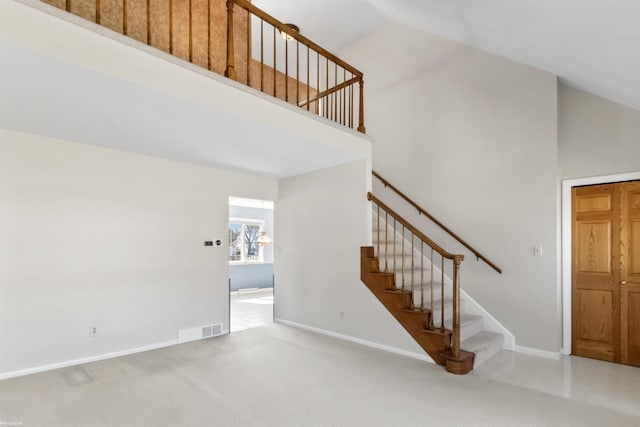 staircase with visible vents, baseboards, high vaulted ceiling, and carpet flooring