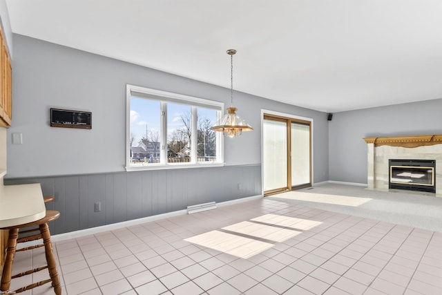 interior space with visible vents, baseboards, a chandelier, a premium fireplace, and tile patterned floors