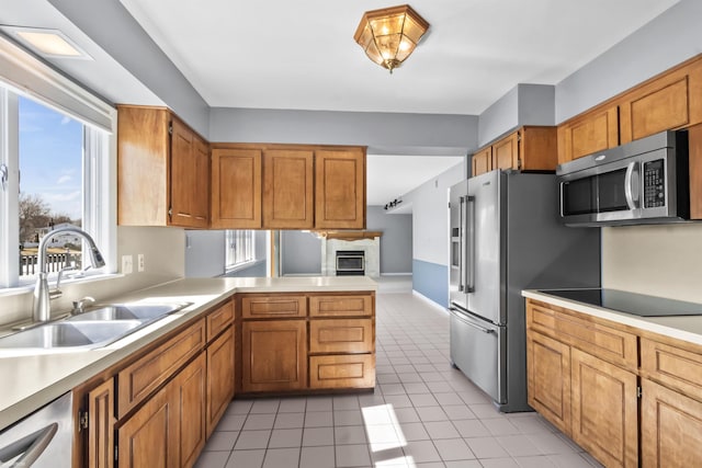 kitchen with appliances with stainless steel finishes, light countertops, a peninsula, and a sink