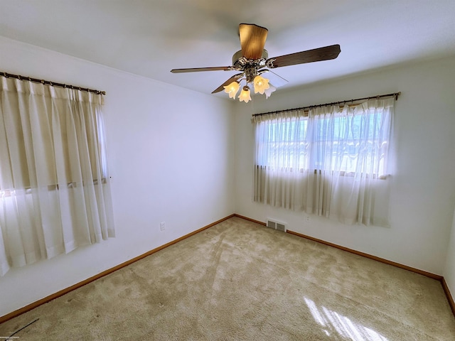 unfurnished room featuring visible vents, baseboards, carpet floors, and ceiling fan