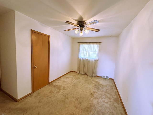 empty room featuring light carpet, baseboards, visible vents, and ceiling fan