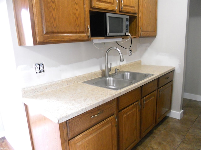 kitchen with stainless steel microwave, brown cabinets, light countertops, and a sink