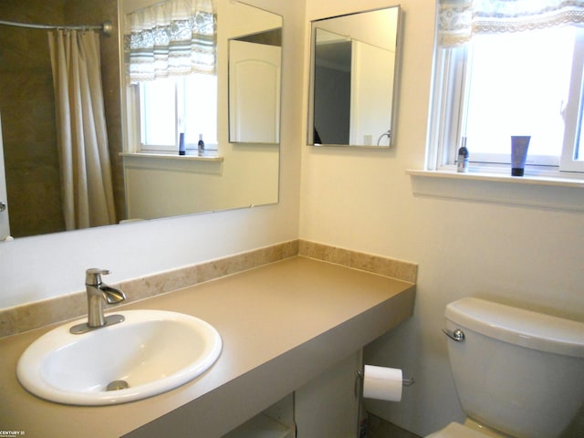 bathroom with a shower with shower curtain, toilet, and vanity