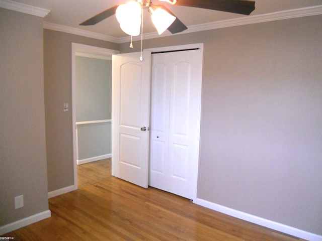 unfurnished bedroom featuring a closet, baseboards, wood finished floors, and ornamental molding