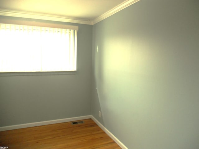 empty room featuring visible vents, baseboards, light wood-style floors, and crown molding