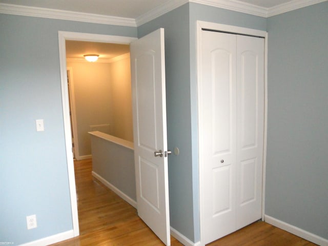 corridor with crown molding, light wood-style flooring, an upstairs landing, and baseboards