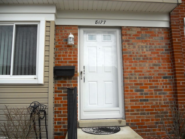 doorway to property with brick siding