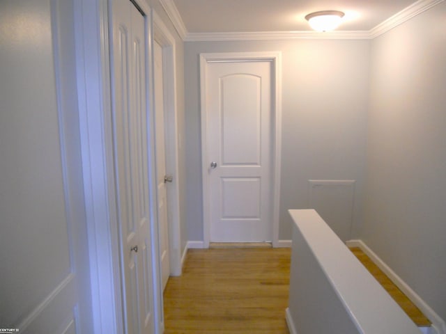 hallway with light wood finished floors, an upstairs landing, baseboards, and ornamental molding