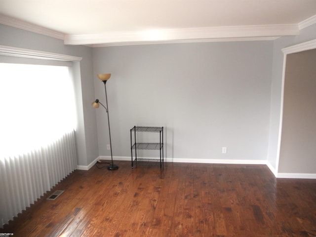 empty room with crown molding, baseboards, visible vents, and wood-type flooring