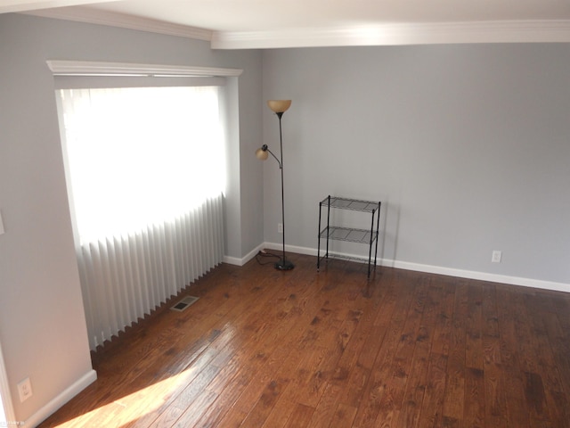 unfurnished room featuring hardwood / wood-style flooring, baseboards, visible vents, and ornamental molding