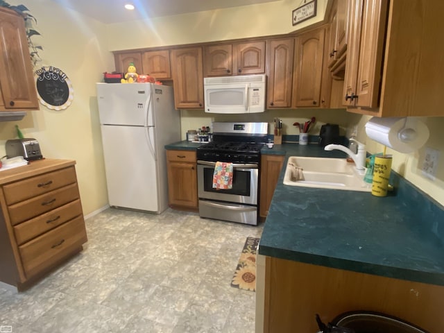 kitchen featuring white appliances, dark countertops, brown cabinetry, and a sink