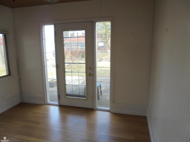 doorway with baseboards and wood finished floors