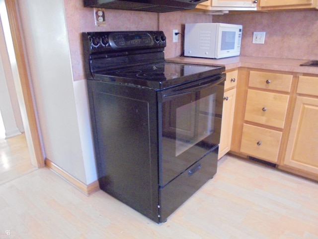 kitchen with white microwave, light brown cabinets, light wood finished floors, electric range, and backsplash