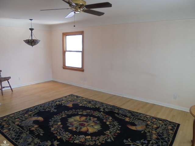 spare room featuring baseboards, light wood-type flooring, and ceiling fan