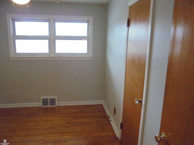 empty room with visible vents, baseboards, a healthy amount of sunlight, and wood finished floors