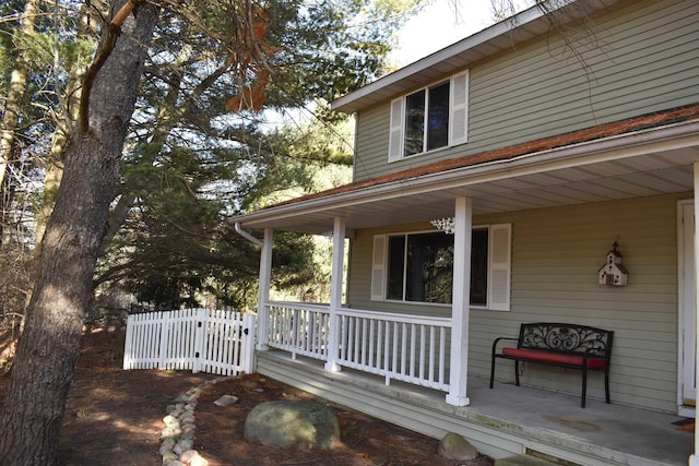 view of home's exterior with covered porch and fence