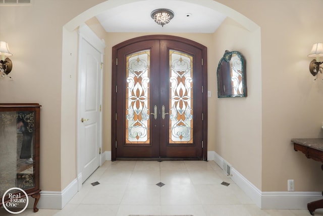 foyer featuring french doors, arched walkways, baseboards, and visible vents